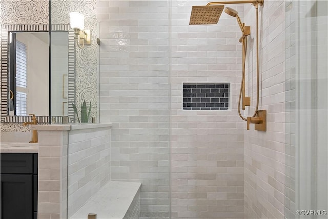 bathroom with a tile shower and vanity