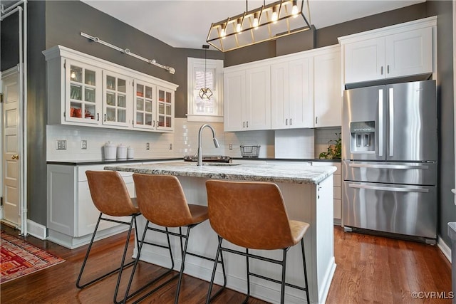 kitchen featuring stainless steel fridge, tasteful backsplash, dark wood-type flooring, and a sink