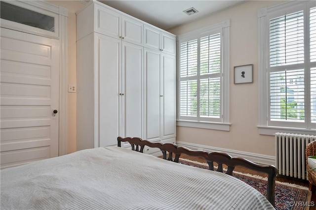 bedroom featuring radiator, multiple windows, and a closet