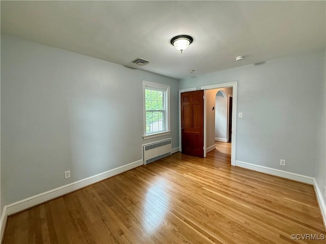 4210 Wistar Rd, Henrico, VA 23228 - unfurnished bedroom with radiator heating unit, baseboards, light wood-style floors, and arched walkways