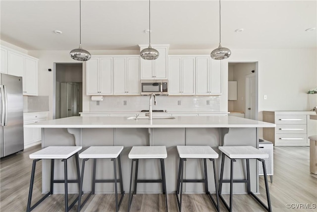 kitchen with stainless steel appliances, tasteful backsplash, white cabinets, and light countertops