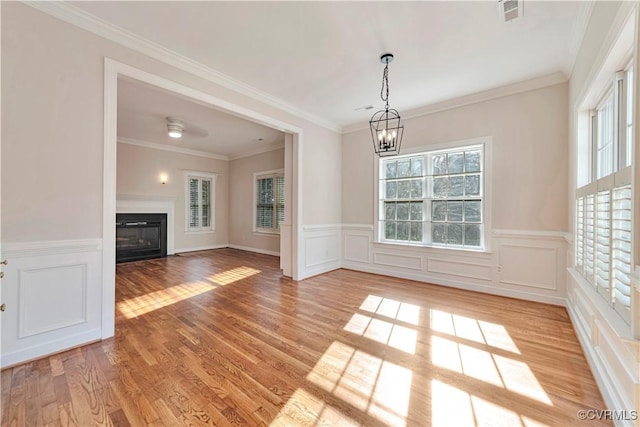 1355 Hawkins Wood Cir, Midlothian, VA 23114 - unfurnished living room featuring a chandelier, a glass covered fireplace, light wood-style floors, a wainscoted wall, and a decorative wall