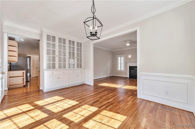 1355 Hawkins Wood Cir, Midlothian, VA 23114 - unfurnished dining area featuring a chandelier, light wood-type flooring, ornamental molding, a glass covered fireplace, and baseboards