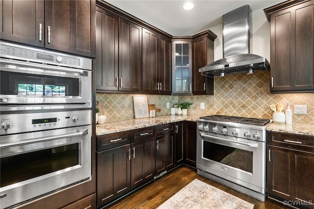 16412 Ravenchase Way, Moseley, VA 23120 - kitchen with wall chimney range hood, stainless steel appliances, light stone countertops, dark wood finished floors, and dark brown cabinetry
