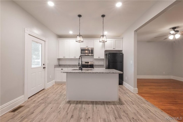kitchen with stainless steel appliances, a sink, recessed lighting, backsplash, and a center island with sink