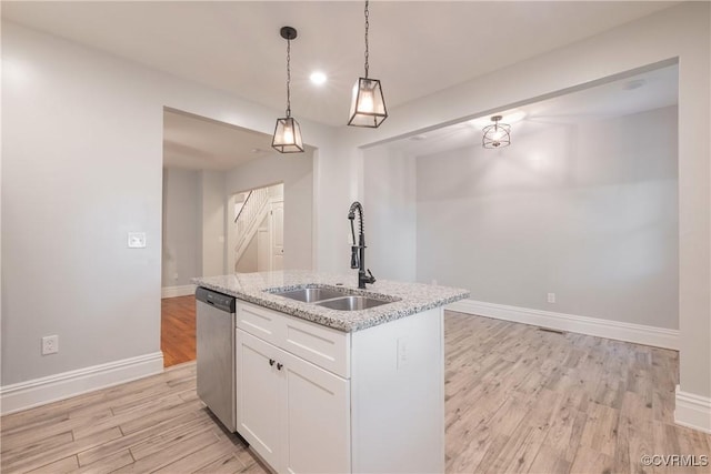 kitchen with a sink, stainless steel dishwasher, light wood-style floors, white cabinetry, and decorative light fixtures