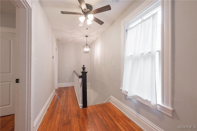 corridor featuring an upstairs landing, wood-type flooring, and baseboards