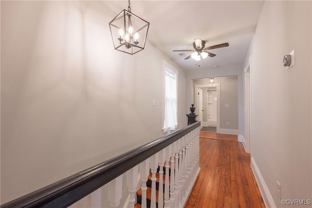 hall with hardwood / wood-style flooring, baseboards, and a chandelier