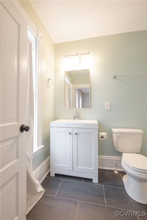half bathroom with baseboards, toilet, tile patterned flooring, and vanity