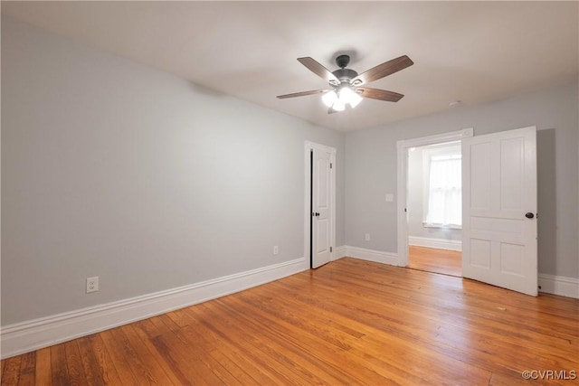 empty room with baseboards, a ceiling fan, and light wood-type flooring