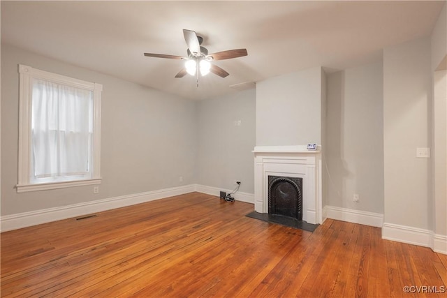 unfurnished living room with hardwood / wood-style floors, a fireplace with flush hearth, baseboards, and ceiling fan
