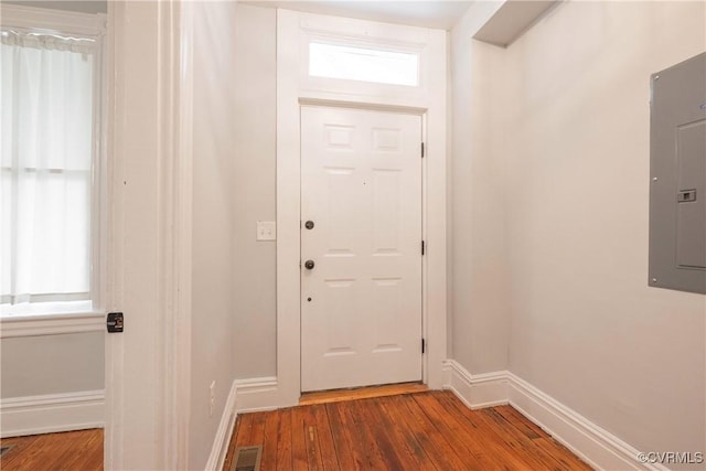 doorway to outside with electric panel, wood finished floors, and baseboards