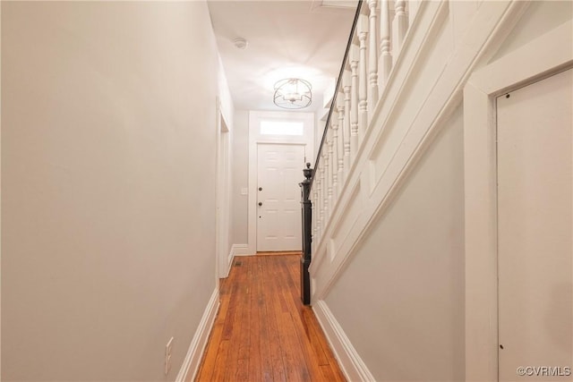 hallway with wood-type flooring, baseboards, and stairway