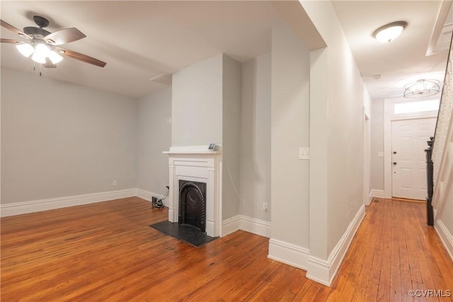unfurnished living room featuring light wood-type flooring, baseboards, and a ceiling fan