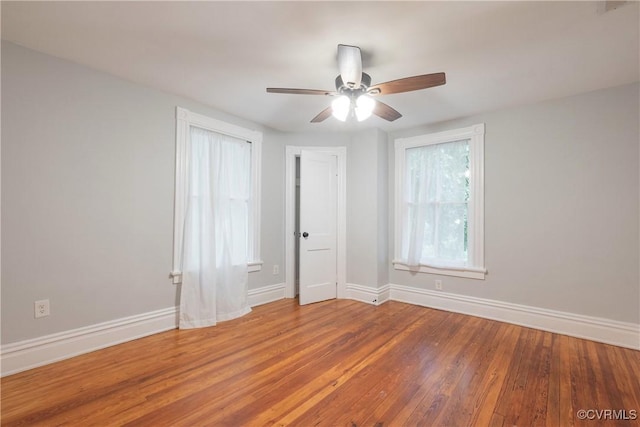 empty room featuring baseboards, wood finished floors, and a ceiling fan