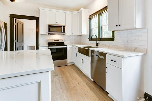 170 Glenmore Ln, Keswick, VA 22947 - kitchen with stainless steel appliances, a sink, light wood finished floors, white cabinetry, and decorative backsplash
