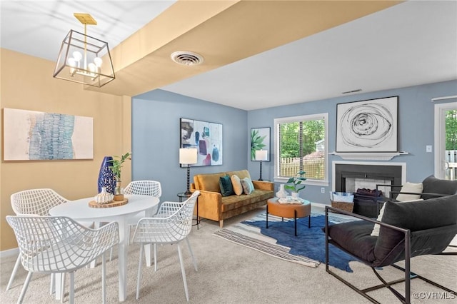 carpeted living area featuring a chandelier, a fireplace, and baseboards