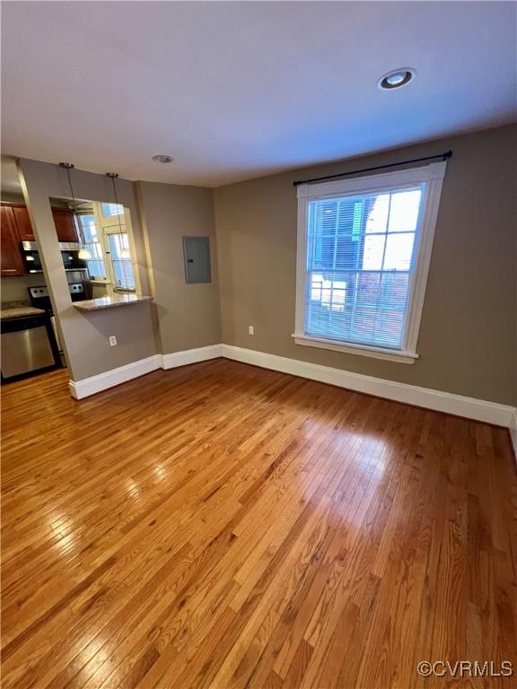 unfurnished living room with electric panel, light wood-style flooring, baseboards, and recessed lighting
