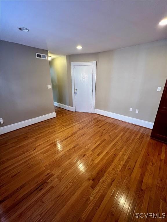 empty room with wood finished floors, baseboards, and recessed lighting