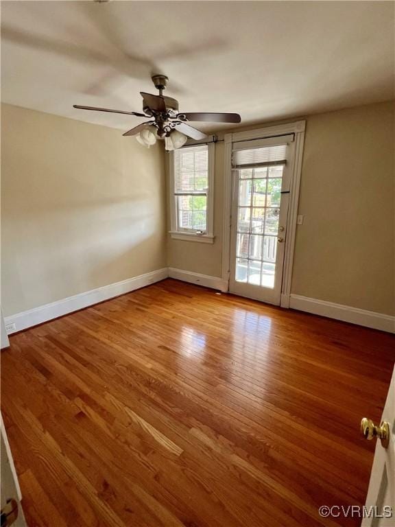 spare room with ceiling fan, wood finished floors, and baseboards