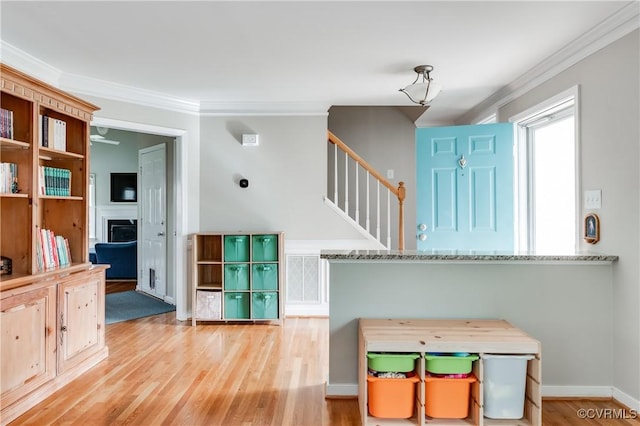 entryway featuring crown molding, a fireplace, wood finished floors, stairs, and ceiling fan
