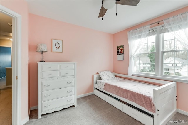 bedroom featuring light colored carpet, baseboards, and a ceiling fan