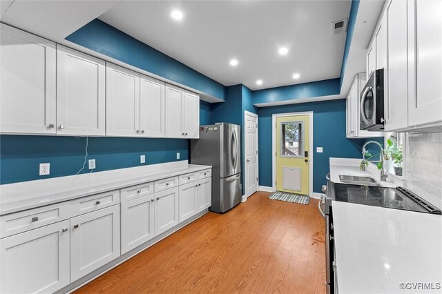 1415 N 25th St, Richmond, VA 23223 - kitchen with appliances with stainless steel finishes, a sink, white cabinets, light countertops, and recessed lighting
