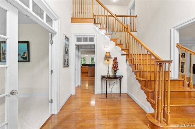 entrance foyer featuring wood finished floors, a towering ceiling, stairs, and baseboards
