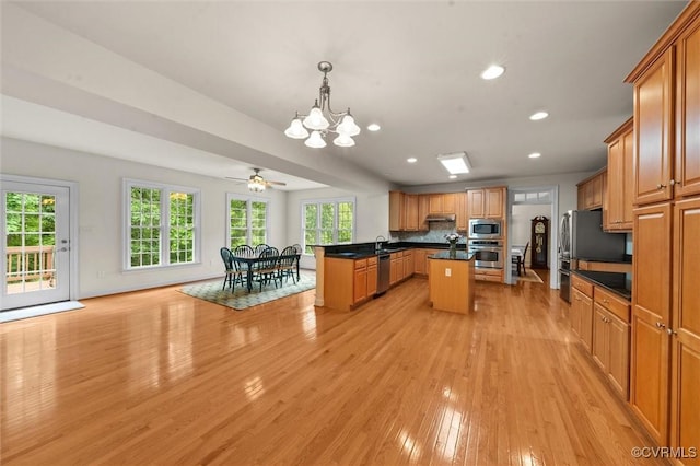 kitchen with appliances with stainless steel finishes, a chandelier, light wood-style floors, dark countertops, and plenty of natural light