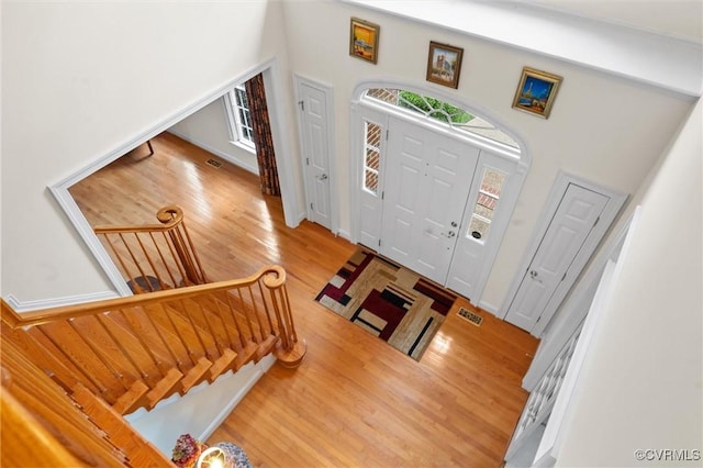 entryway with wood finished floors, stairs, and a high ceiling