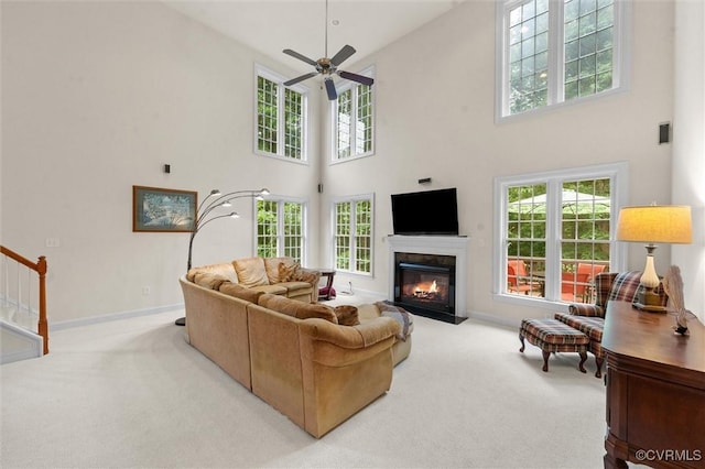 living room with carpet, a high ceiling, a fireplace with flush hearth, and healthy amount of natural light