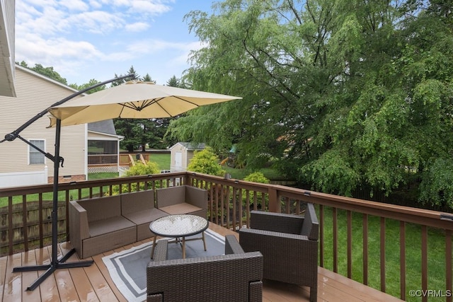 wooden terrace featuring outdoor lounge area, a shed, and an outbuilding