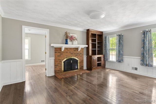 unfurnished living room with wainscoting, hardwood / wood-style floors, a fireplace, and ornamental molding
