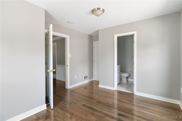 unfurnished bedroom with wood finished floors, baseboards, and ensuite bathroom