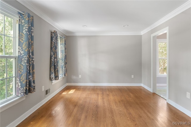 empty room with wood finished floors, baseboards, and ornamental molding