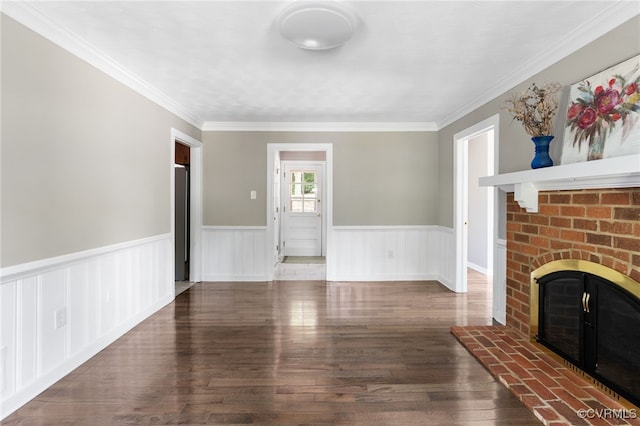 unfurnished living room with a brick fireplace, a wainscoted wall, wood finished floors, and crown molding