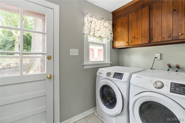 laundry room with washing machine and dryer, cabinet space, plenty of natural light, and baseboards