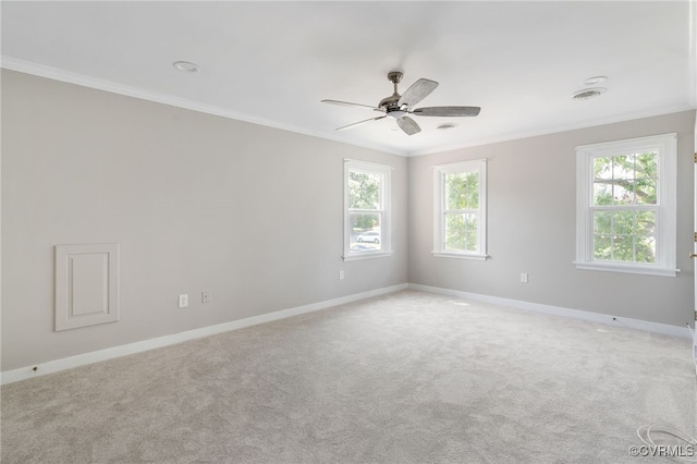 spare room featuring crown molding, baseboards, a ceiling fan, and light colored carpet
