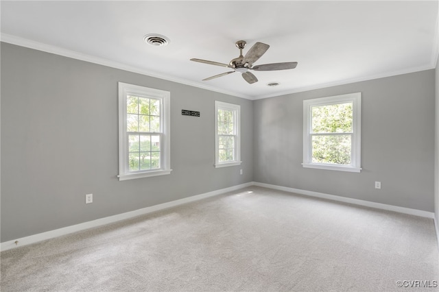 carpeted spare room featuring crown molding, baseboards, and a ceiling fan