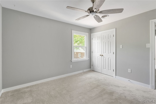 unfurnished bedroom with light colored carpet, baseboards, a closet, and a ceiling fan