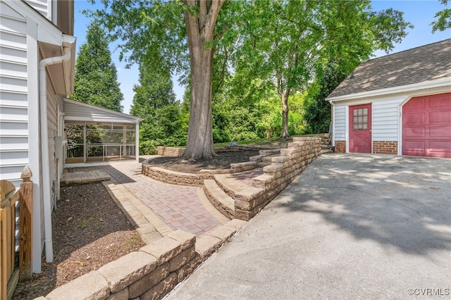 view of yard featuring a sunroom, a garage, and driveway