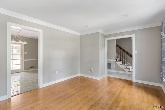 spare room featuring a chandelier, stairway, light wood finished floors, baseboards, and crown molding
