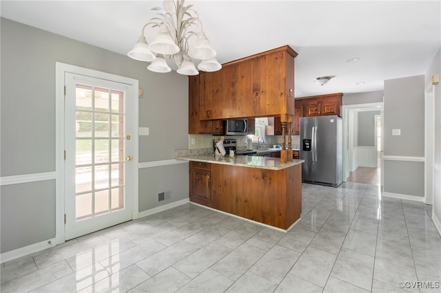 kitchen featuring appliances with stainless steel finishes, a chandelier, a peninsula, a sink, and baseboards
