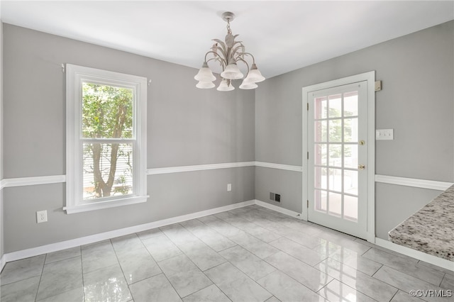 unfurnished dining area featuring a chandelier, baseboards, and tile patterned floors