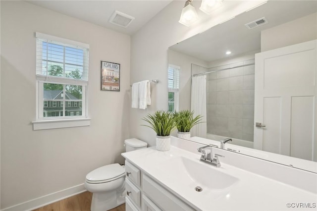 full bath with plenty of natural light, baseboards, wood finished floors, and toilet