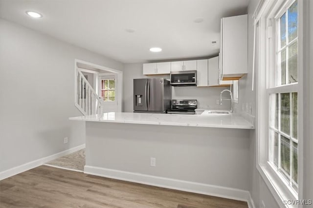 201 W Roanoke St, Ridgeway, VA 23225 - kitchen featuring stainless steel appliances, a sink, a peninsula, baseboards, and light wood-style floors