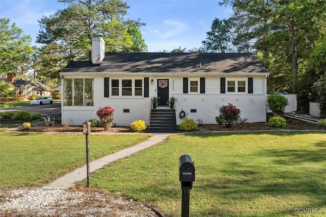 single story home featuring a chimney, a front yard, and brick siding