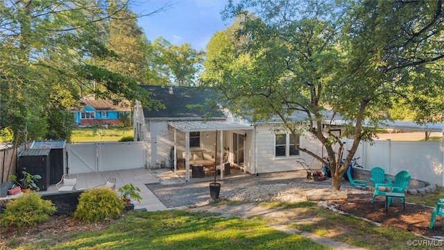back of house with a fenced backyard, a patio area, a storage unit, an outdoor structure, and a gate