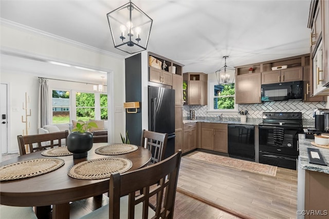 kitchen featuring black appliances, a chandelier, decorative backsplash, a sink, and healthy amount of natural light