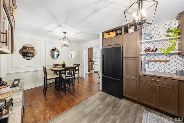 kitchen with freestanding refrigerator, a chandelier, backsplash, open shelves, and crown molding